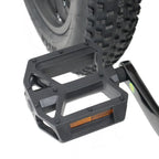 Black bike pedal with orange reflector against a white background
